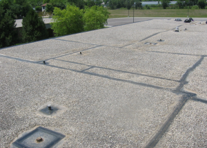 PHOTO 1: This EPDM roof’s service has been extended for nine years and counting, approaching 30 years in-situ performance. Here, the restoration of perimeter gravel- stop flashing and lap seams, as well as detailing of roof drains, penetrations and roof curbs, is nearing completion.